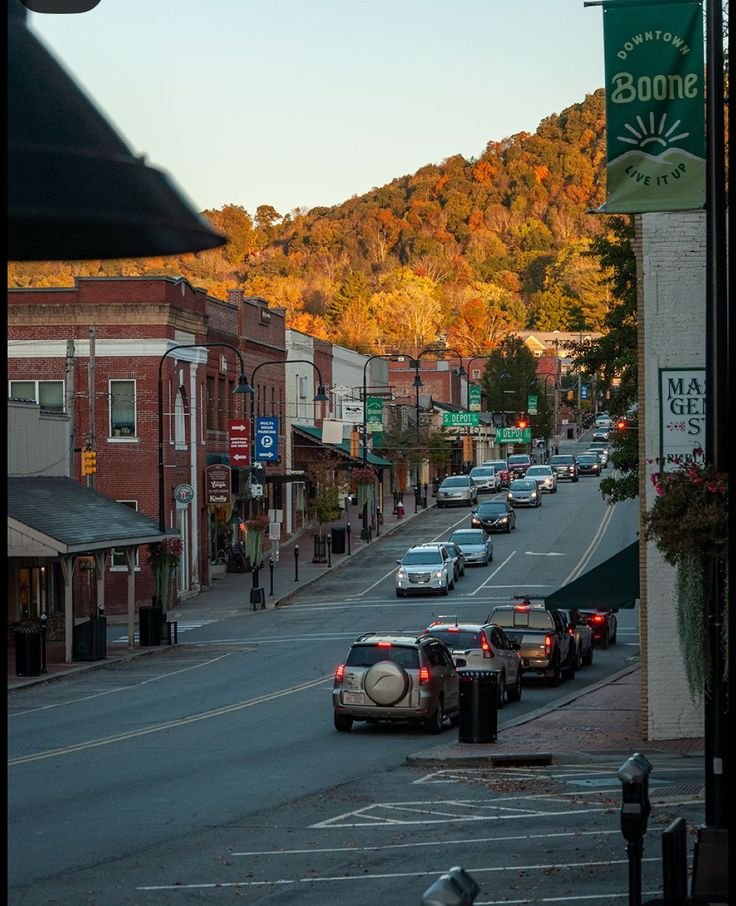 This may contain: cars are parked on the street in front of buildings and trees with fall foliage behind them