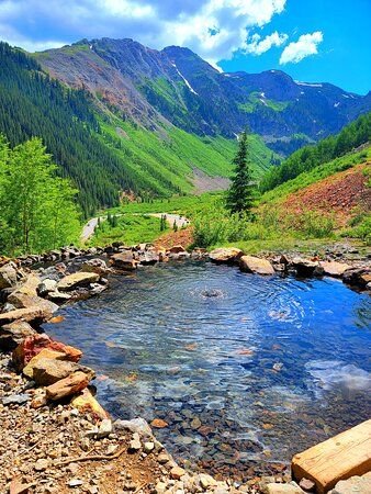 This may contain: there is a small stream in the middle of this mountain valley with mountains in the background