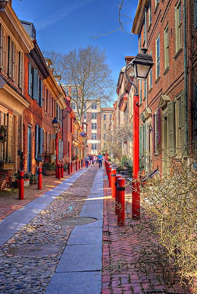 This may contain: a street lined with brick buildings and red post lights
