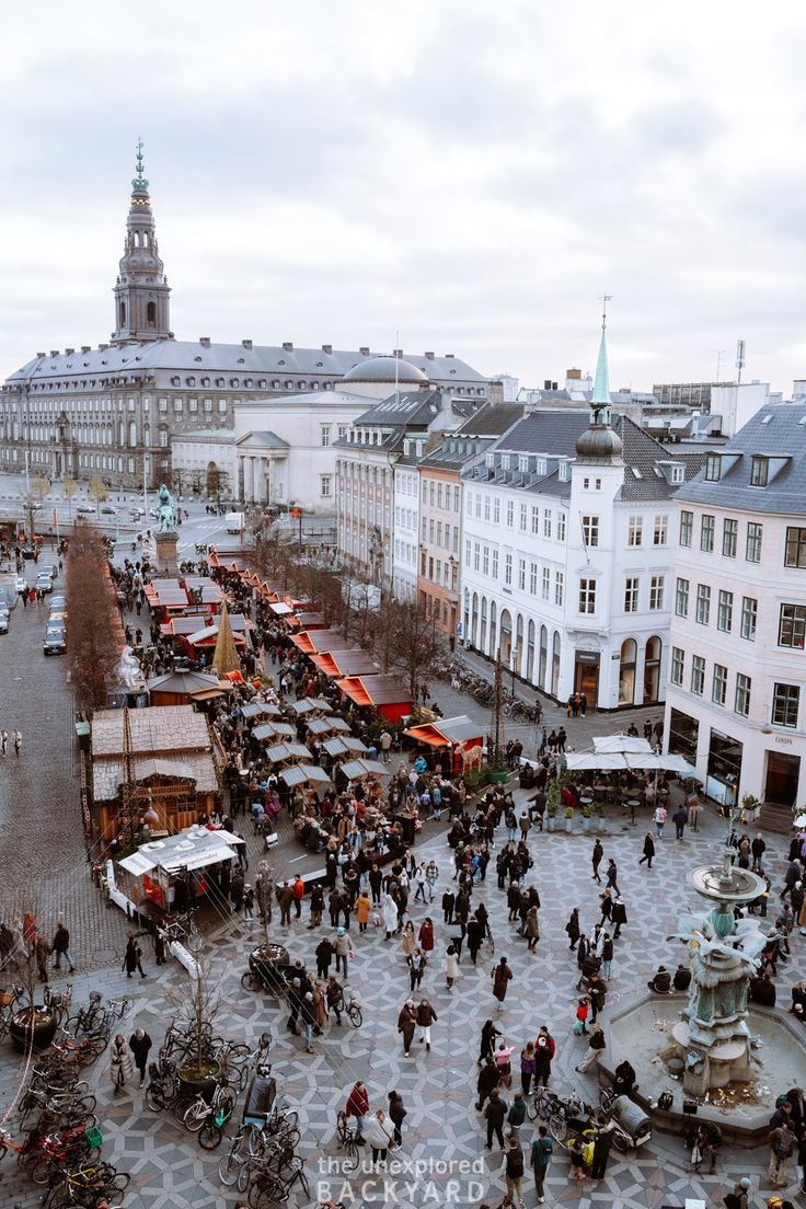 This may contain: an aerial view of a city square with people walking around and vendors on the street