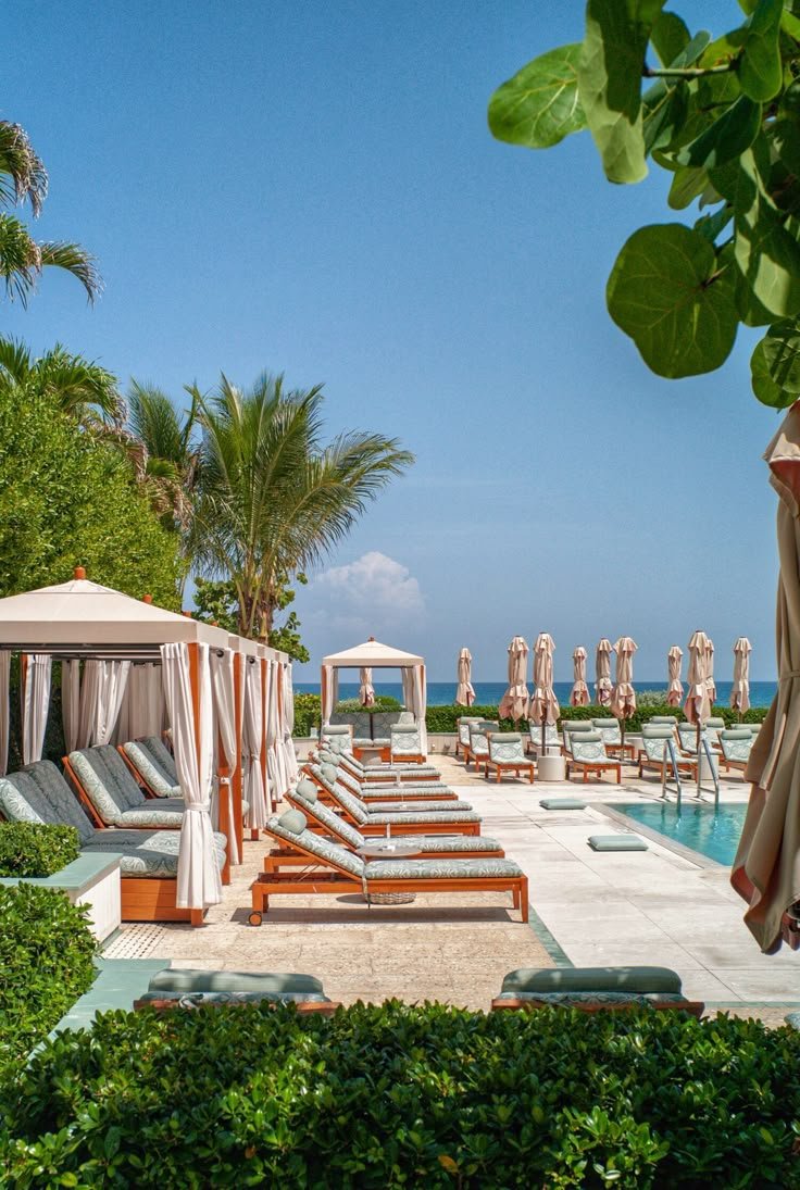 This may contain: an outdoor pool with lounge chairs and umbrellas