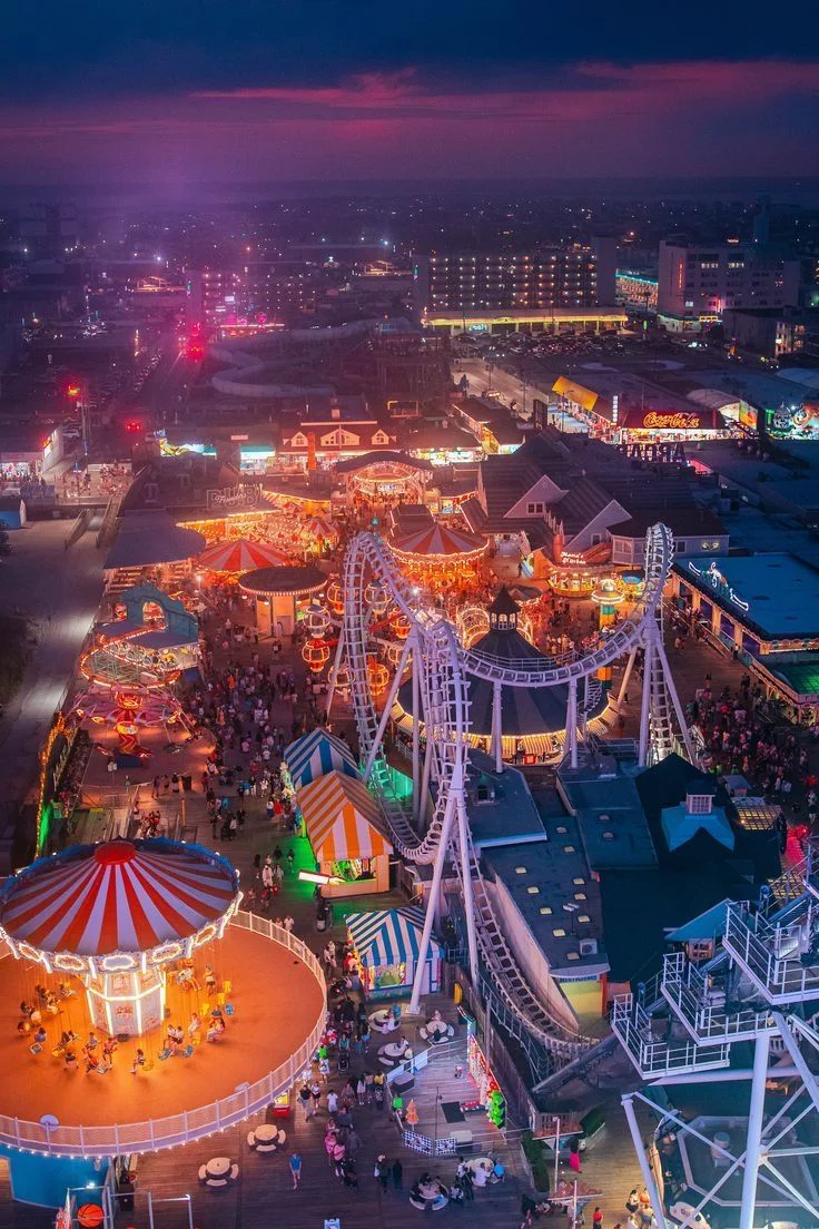 This may contain: an aerial view of the fairground at night, with ferris wheel and carnival rides