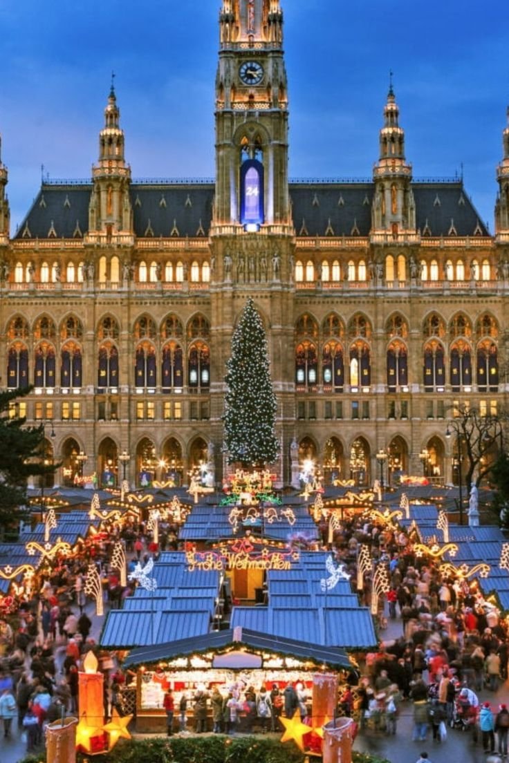 This may contain: an outdoor christmas market in front of a large building with a clock on it's tower