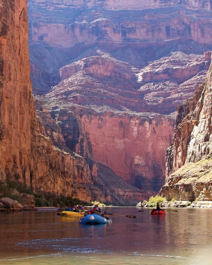 This may contain: some people are rafting down a river in the middle of canyons and cliffs
