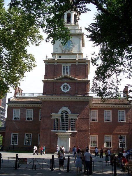 This may contain: people are standing in front of a building with a clock tower on it's side