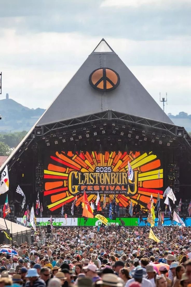 This may contain: a large crowd is gathered at a music festival in front of a stage with flags and banners