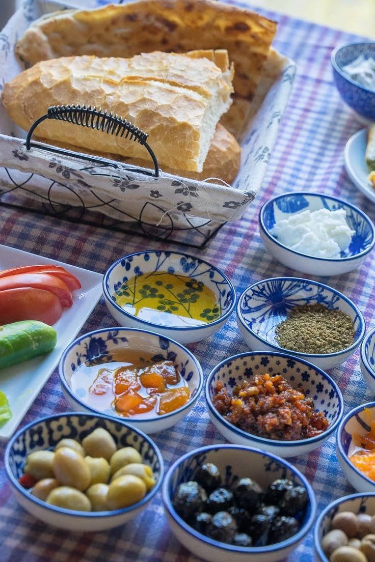 This may contain: a table topped with bowls filled with different types of food next to bread and vegetables