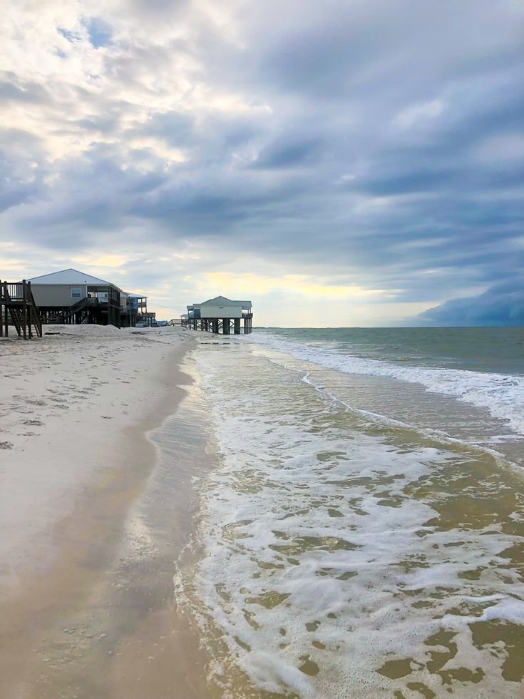 This may contain: the beach has waves coming in from the water and houses on the pier behind it