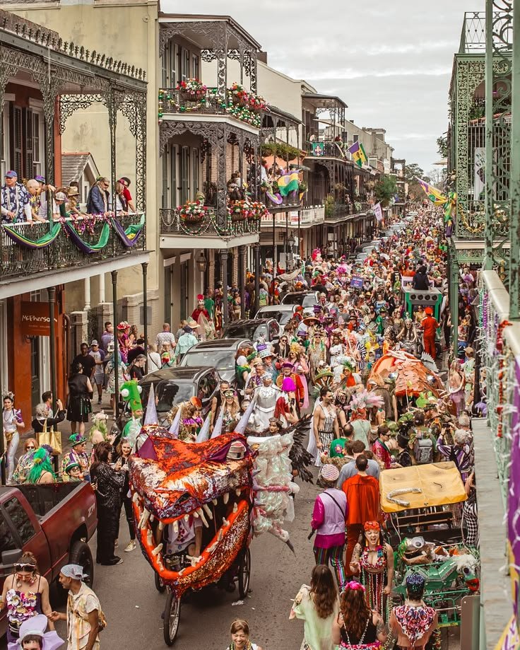 This may contain: a crowded city street filled with lots of people and colorful floats on top of buildings