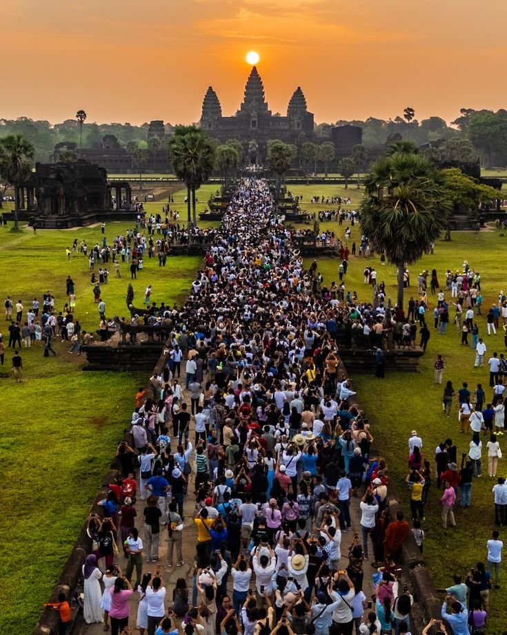 This may contain: a large group of people standing on top of a lush green field
