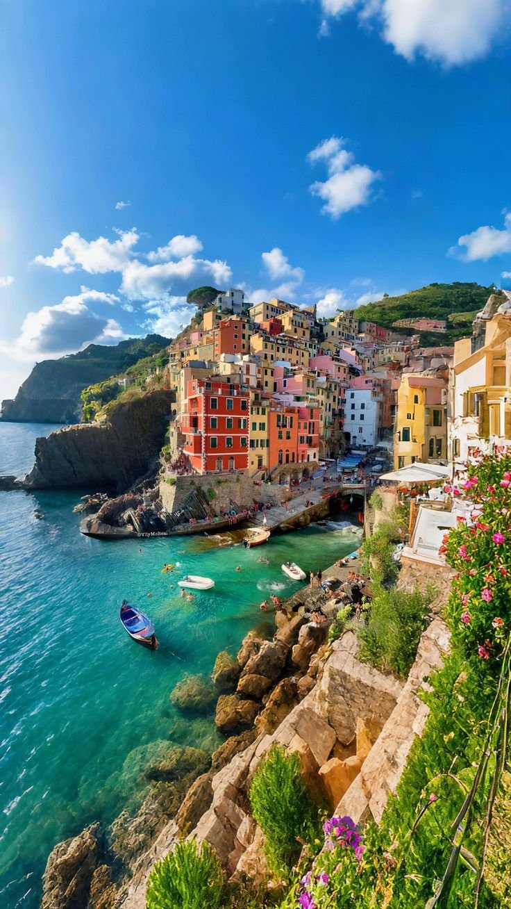 This may contain: boats are parked on the shore in front of colorful houses and cliffs near the ocean