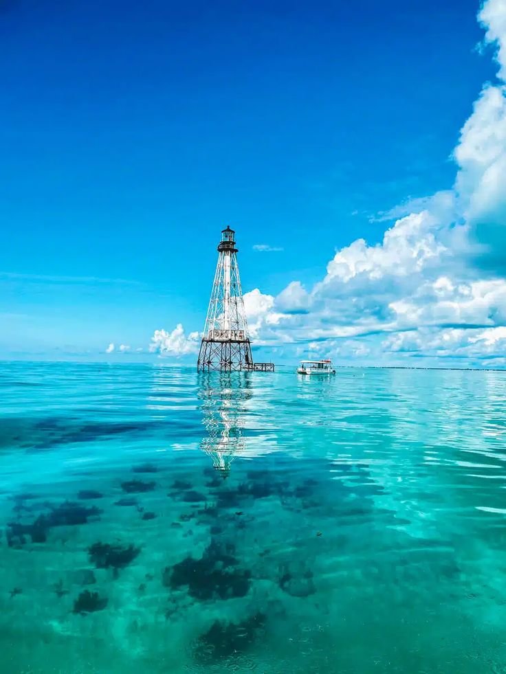 This may contain: the water is very clear and blue with clouds in the sky above it, while two boats are out on the ocean
