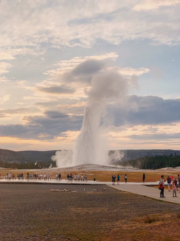 This may contain: people are standing in front of a geyser