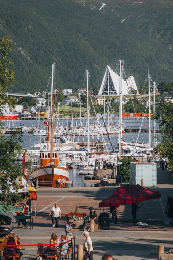 This may contain: many boats are docked in the water near some trees and people sitting at tables with umbrellas