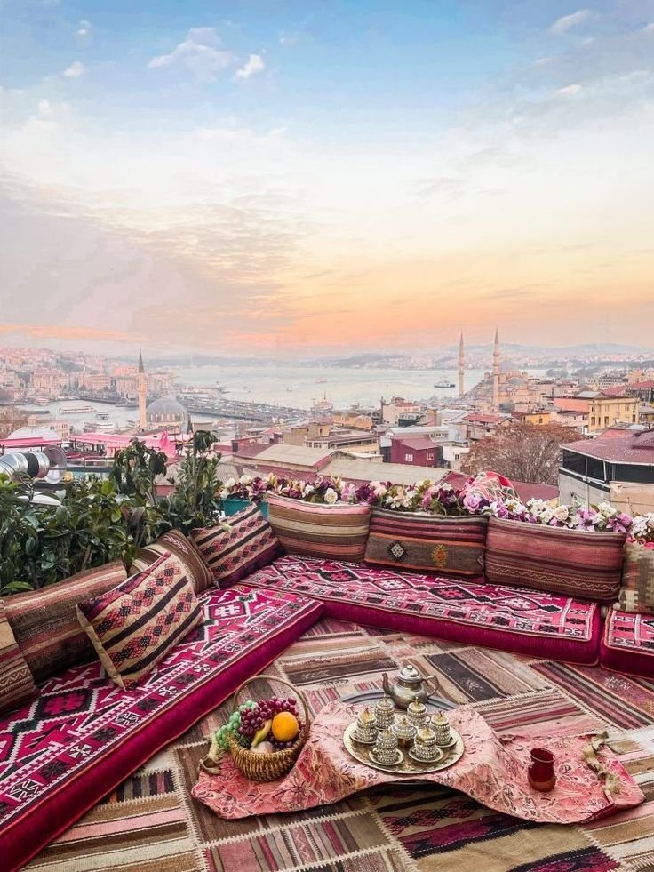This may contain: an outdoor seating area on top of a building overlooking the city and water at sunset