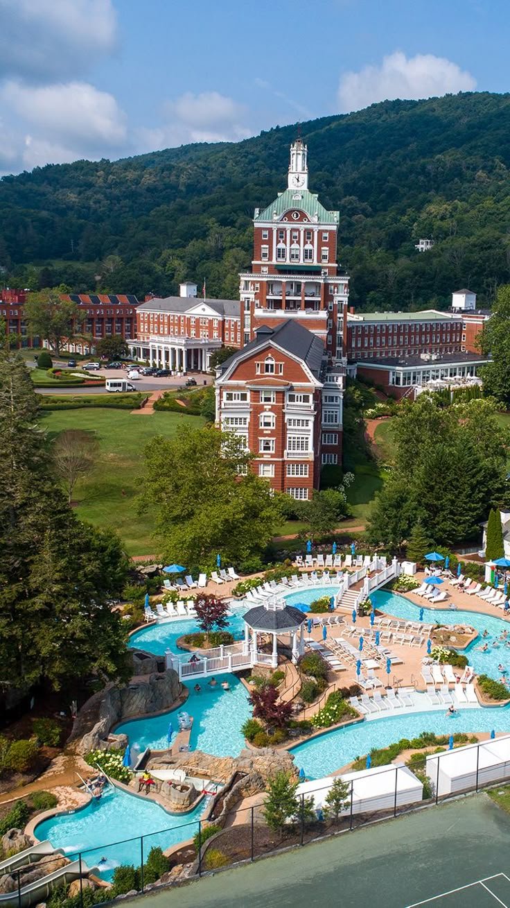 This may contain: an aerial view of a resort with a pool and tennis court in the foreground