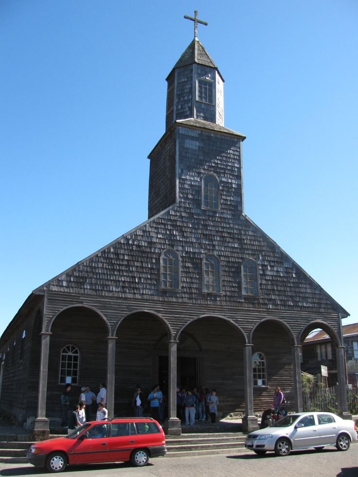 This may contain: an old wooden church with cars parked in front