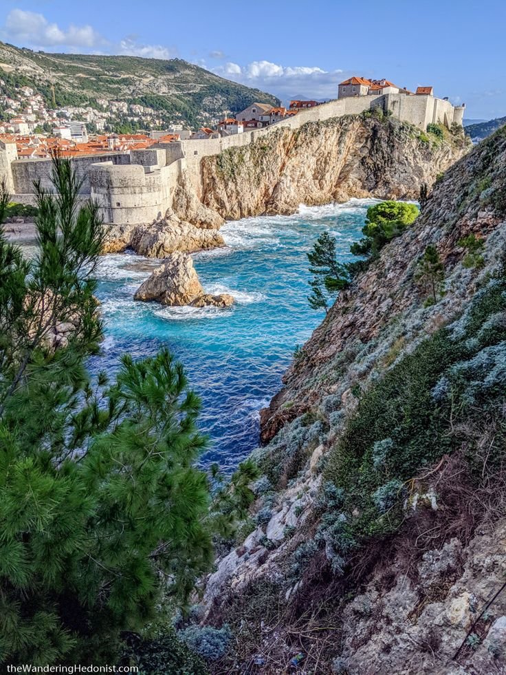 This may contain: the coast is lined with rocky cliffs and blue water, as seen from an overlook point