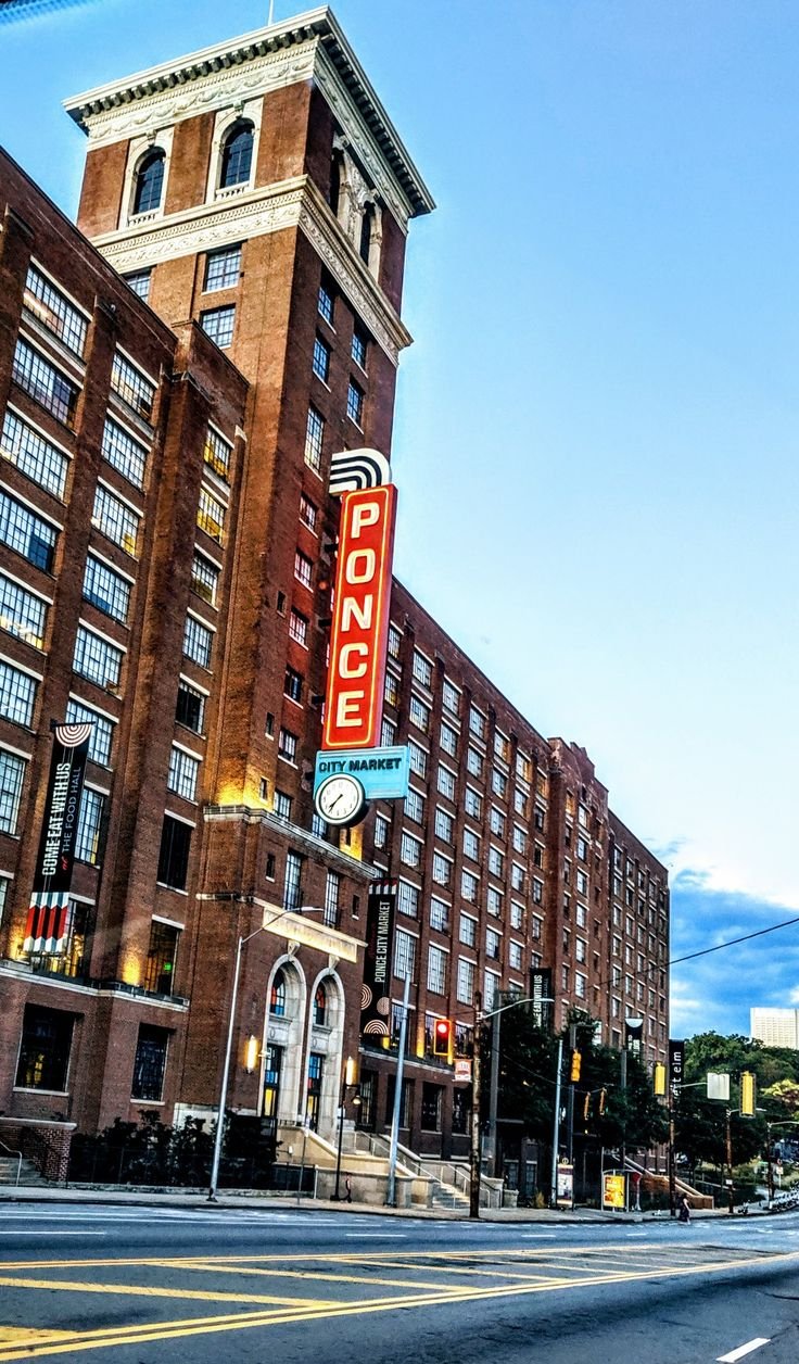 This may contain: an old brick building with a neon sign on it's side next to a street