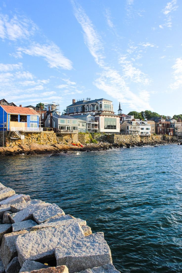 This may contain: a body of water with buildings on the shore and blue sky in the back ground