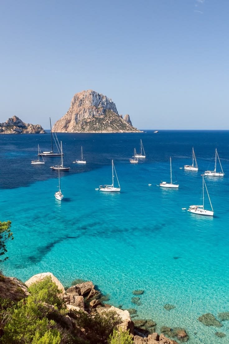 This may contain: many sailboats are in the clear blue water