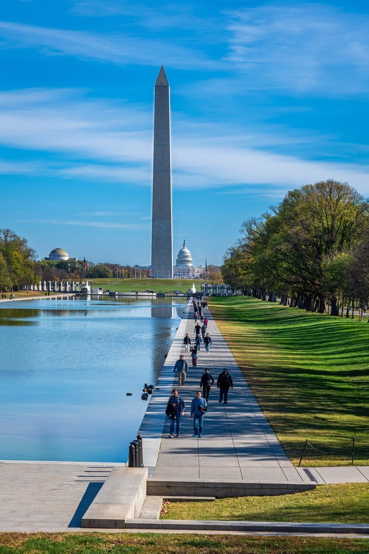 This may contain: people walking along the reflecting walkway in front of the washington monument