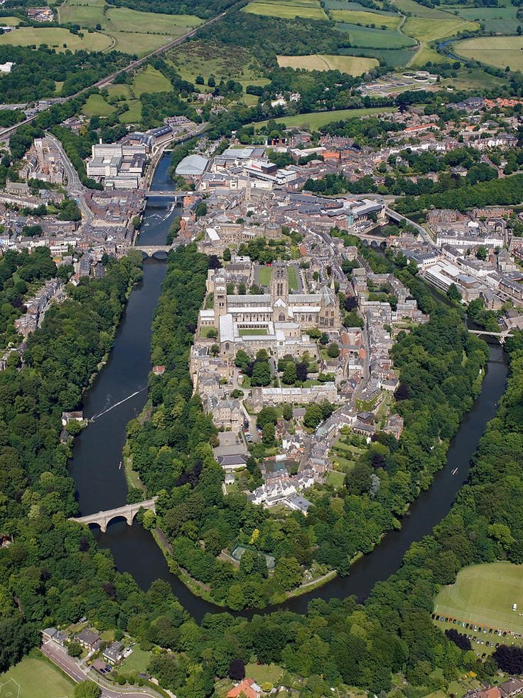 This may contain: an aerial view of a large city with lots of green trees and buildings on both sides of the river
