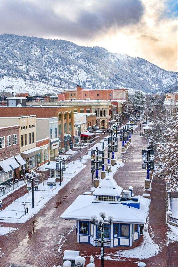 This may contain: the town is covered in snow and has mountains in the backgrouds behind it