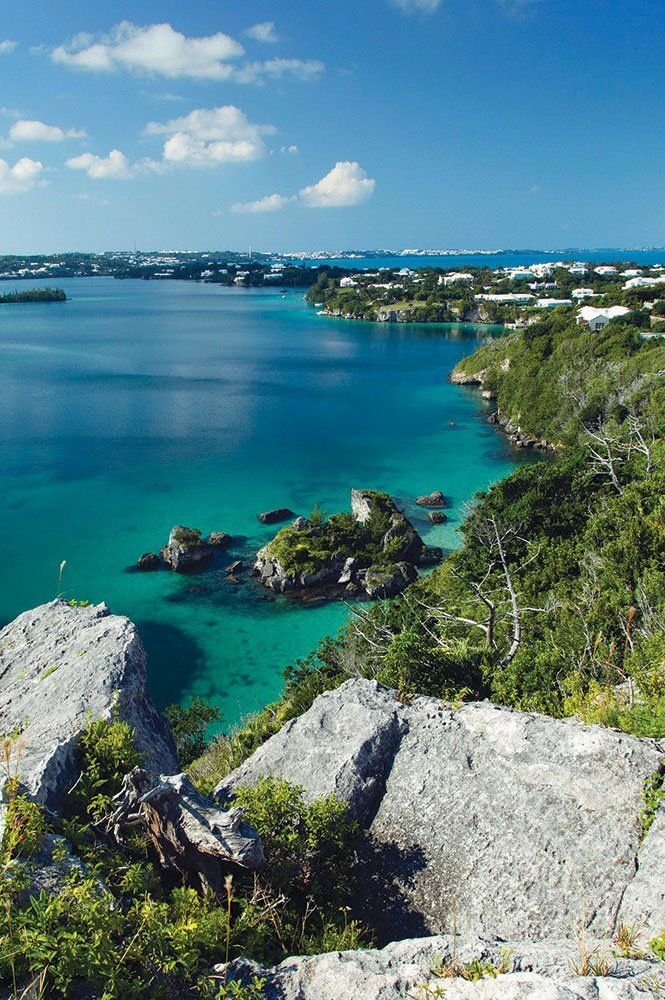 This may contain: the blue water is surrounded by rocks and greenery on both sides of the bay