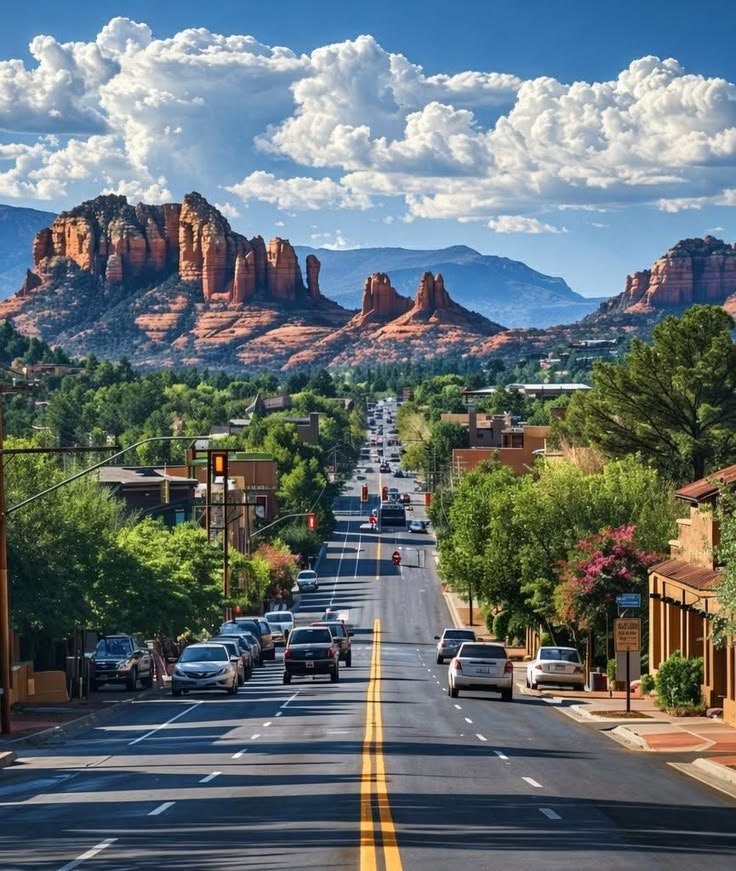 This may contain: cars are parked on the side of an empty street in front of red rock formations