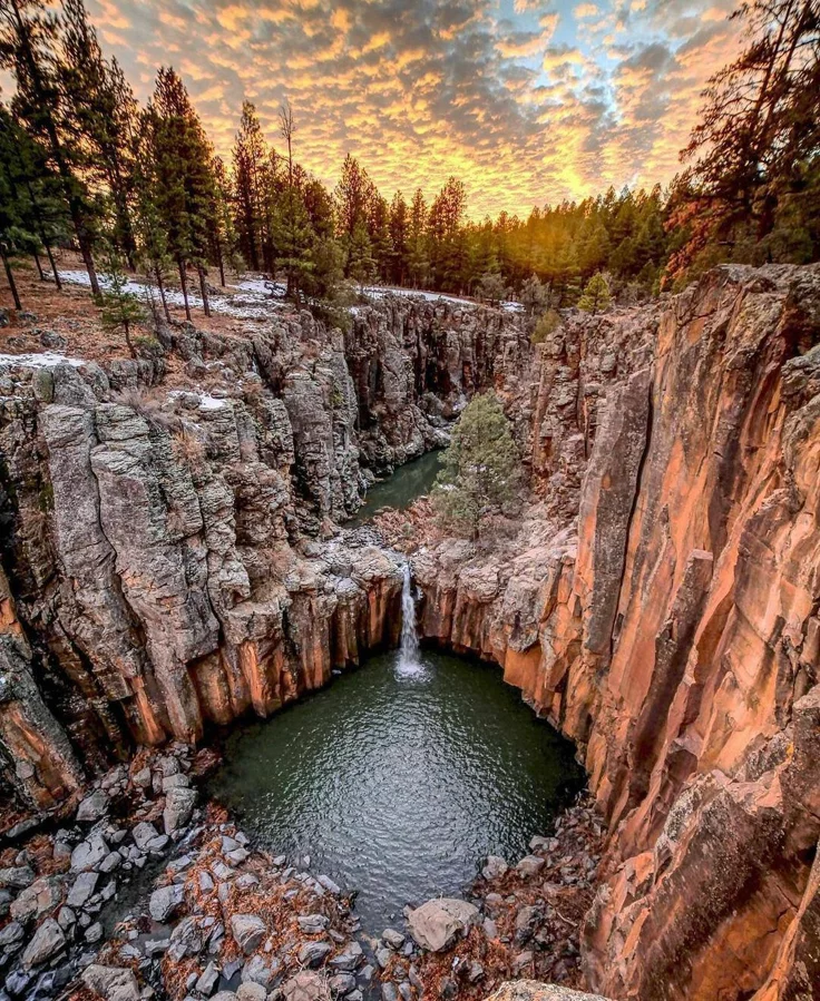 This may contain: a small waterfall in the middle of a canyon