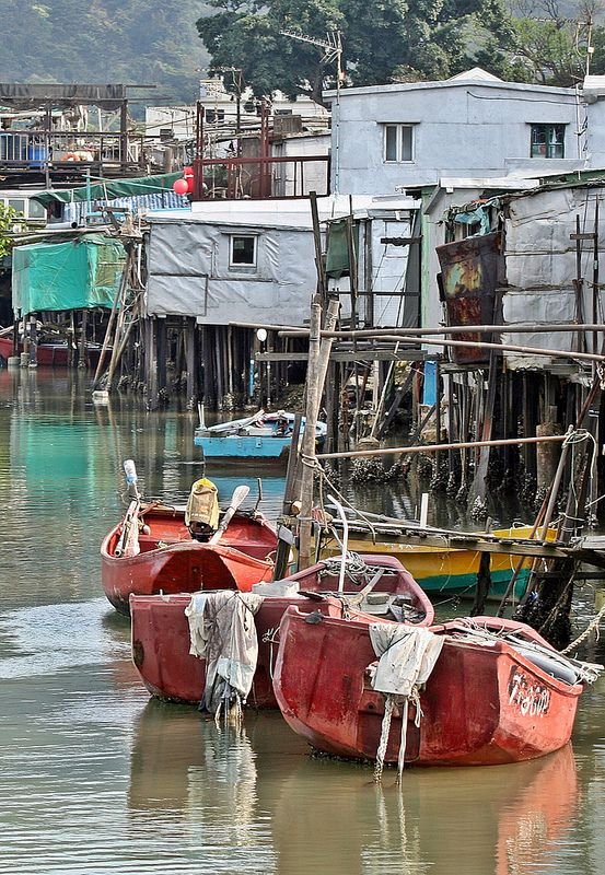 This may contain: several small boats in the water next to some houses and shacks on stilts