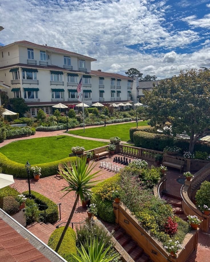 This may contain: an aerial view of a courtyard with many plants and trees in the foreground, surrounded by buildings
