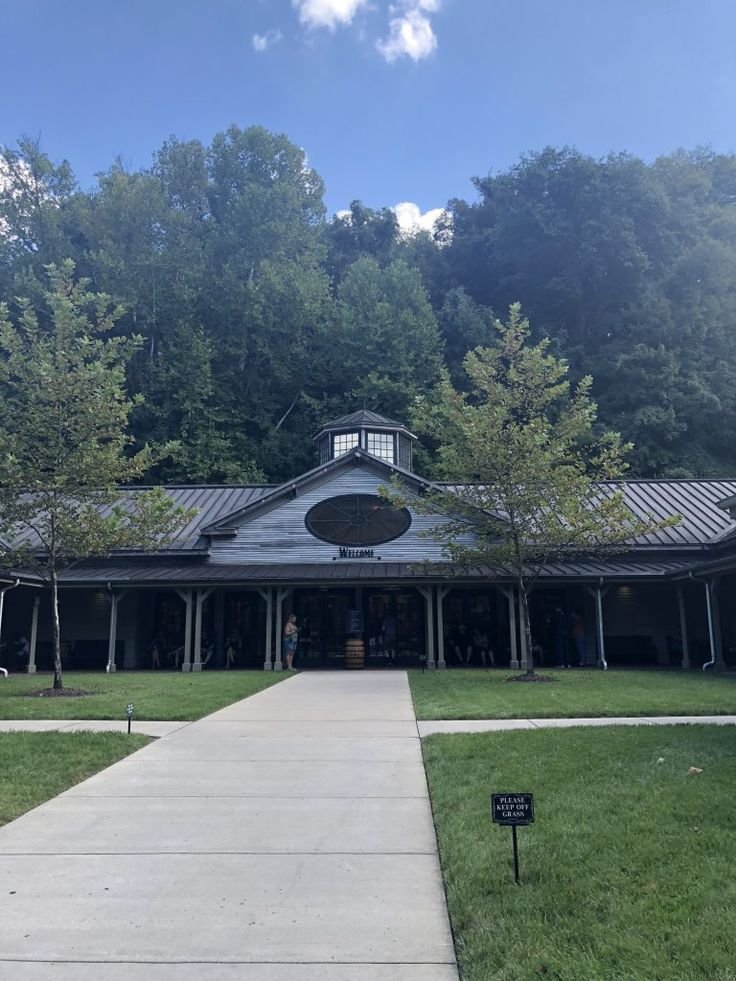This may contain: a building with a walkway leading to it in front of trees and grass on both sides