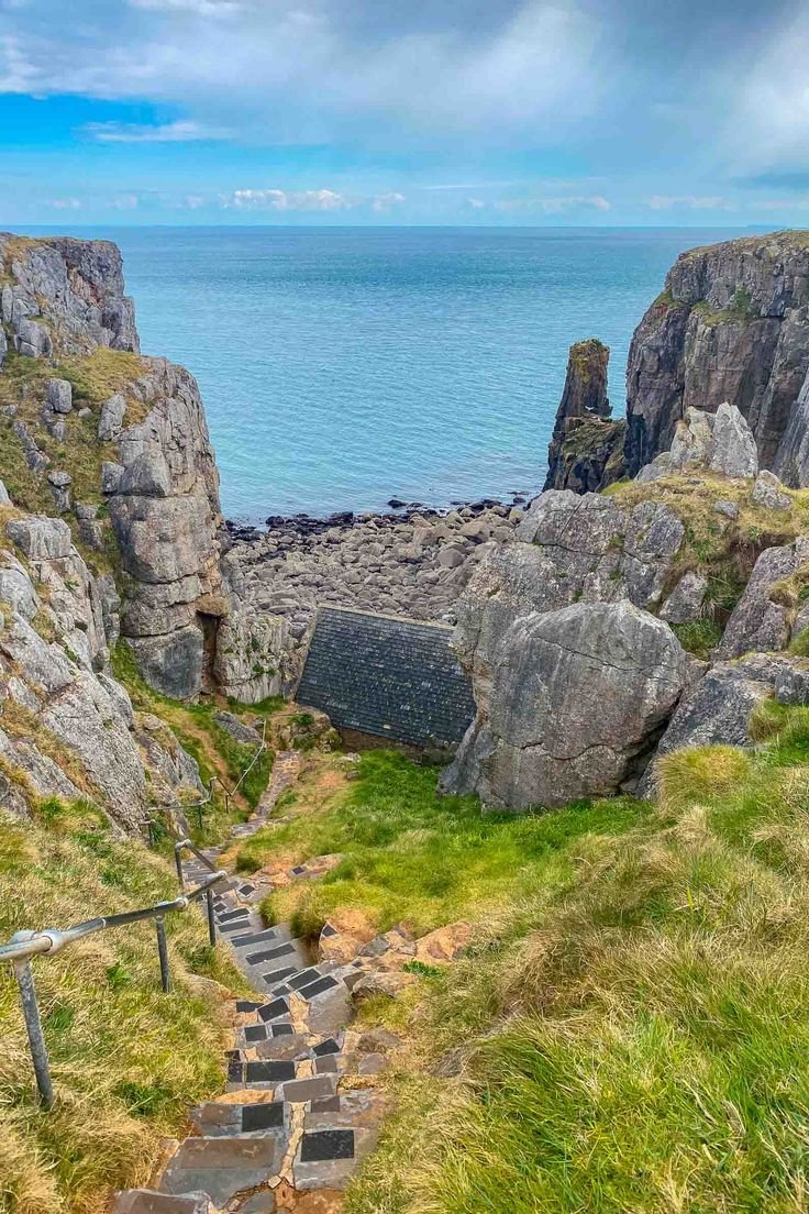 This may contain: stairs leading up to the top of a cliff overlooking the ocean and cliffs in the distance