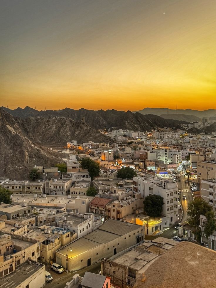 This may contain: an aerial view of a city with mountains in the background at sunset or sunrise time
