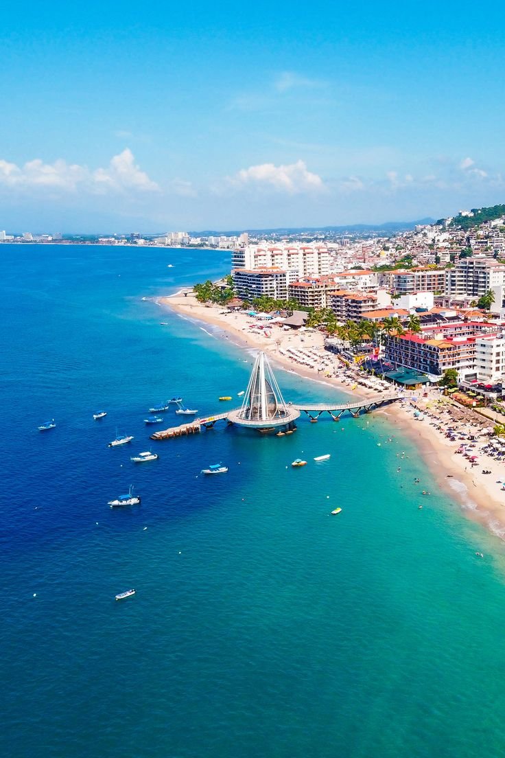 This may contain: an aerial view of a beach with boats in the water and buildings on either side