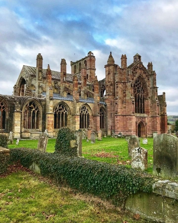 This may contain: an old church with ivy growing on it's walls and graveyard in the foreground