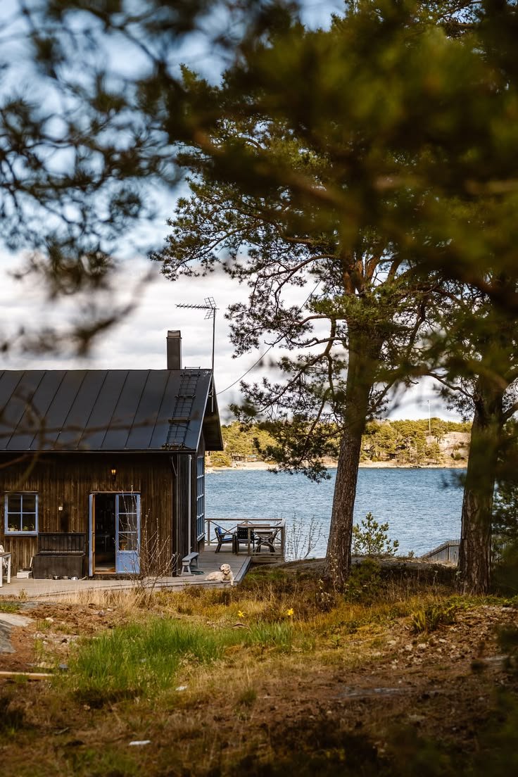 This may contain: a small cabin sits next to the water