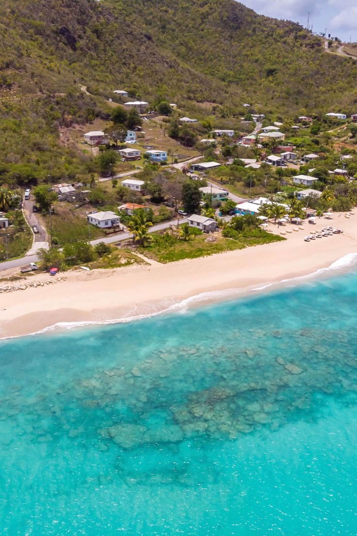 This may contain: an aerial view of the beach and ocean with houses in the distance, surrounded by mountains
