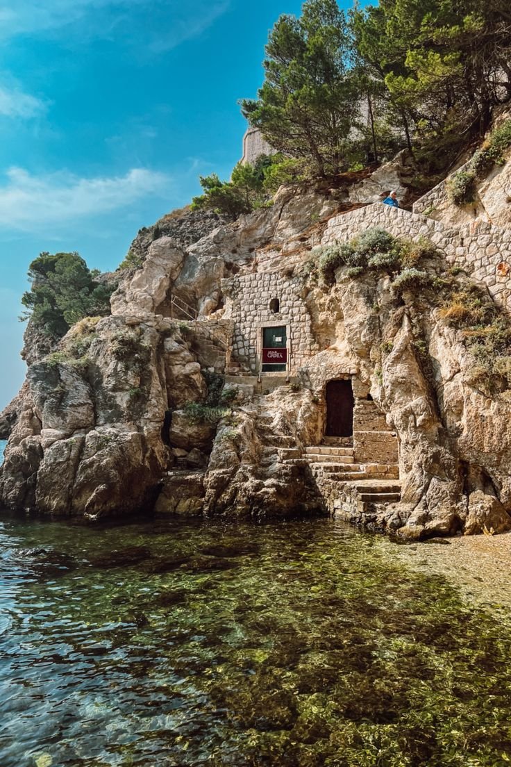 This may contain: the stairs lead up to an old stone building on top of a cliff by the ocean