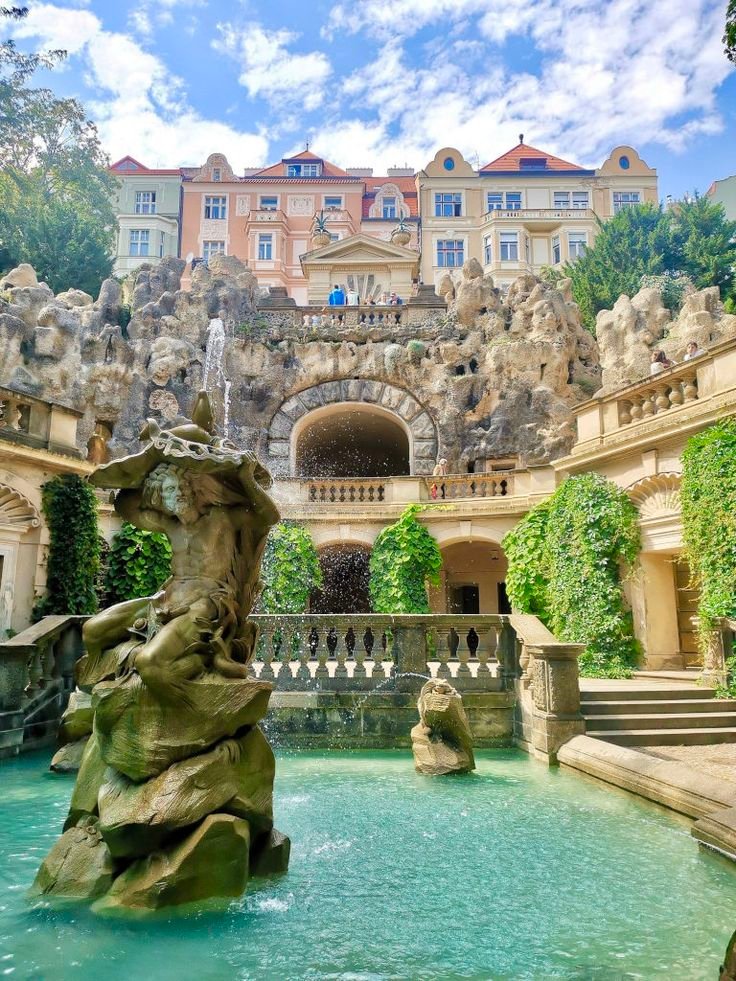 This contains: The grotto in prague with a fountain and a fake cave in the background