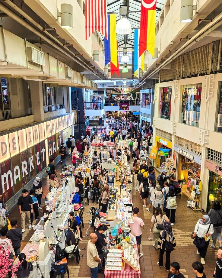 This may contain: an indoor market filled with lots of people and colorful flags hanging from the ceiling above