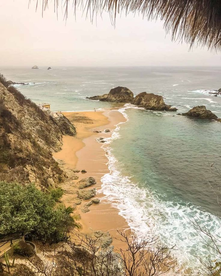 This may contain: the beach is next to some rocks and water
