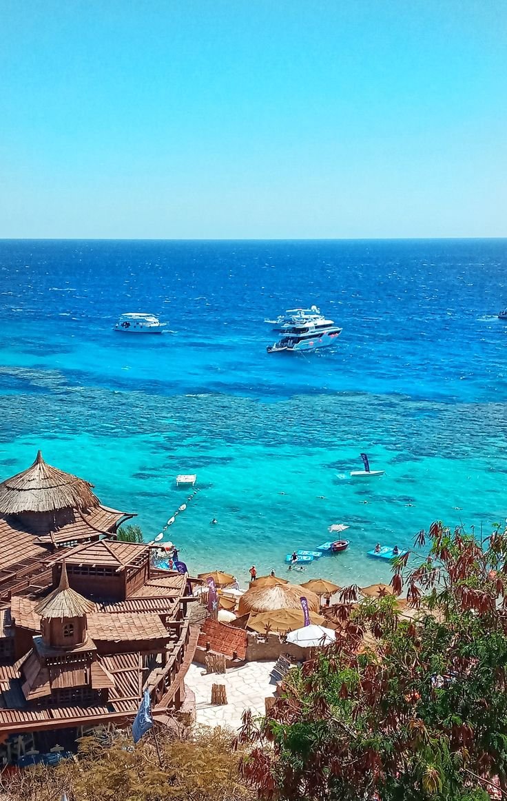 This may contain: several boats are in the water near a beach