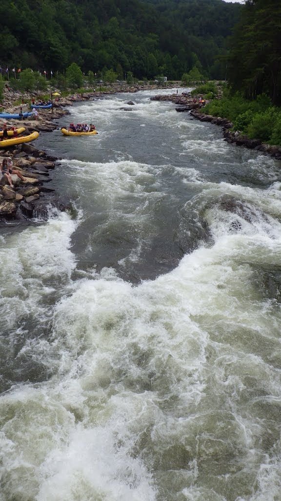 This may contain: a river filled with lots of white water rafters next to rocks and trees in the background