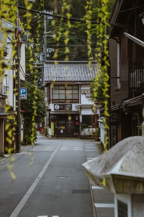 This may contain: an empty street with buildings and trees in the background